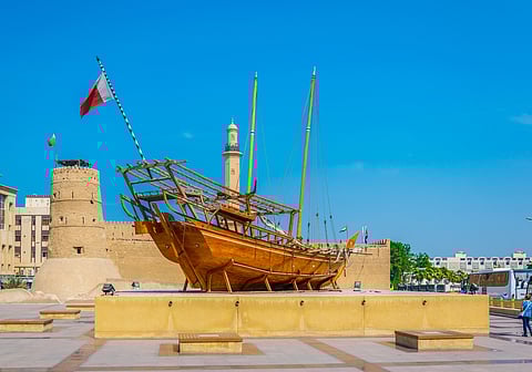 An old wooden dhow in front of the Al Fahidi Fort